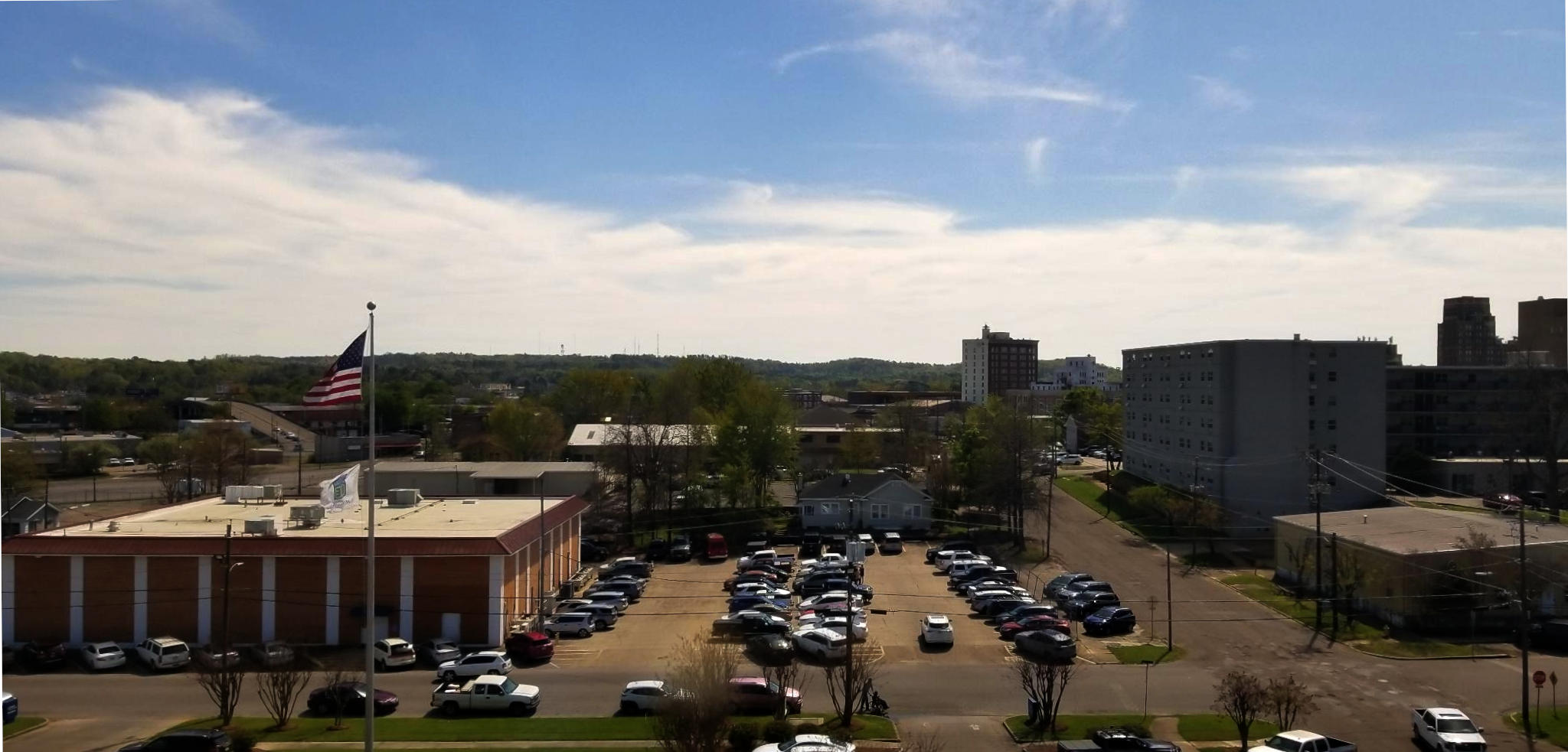 The view of a town view, as seen from above, leading out to hill visible in the distance.