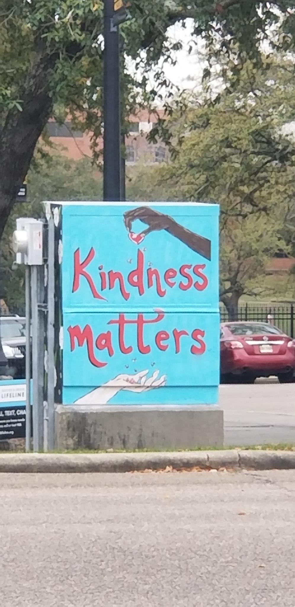 A utility-box mural portraying two hands and the words 'Kindness Matters'.