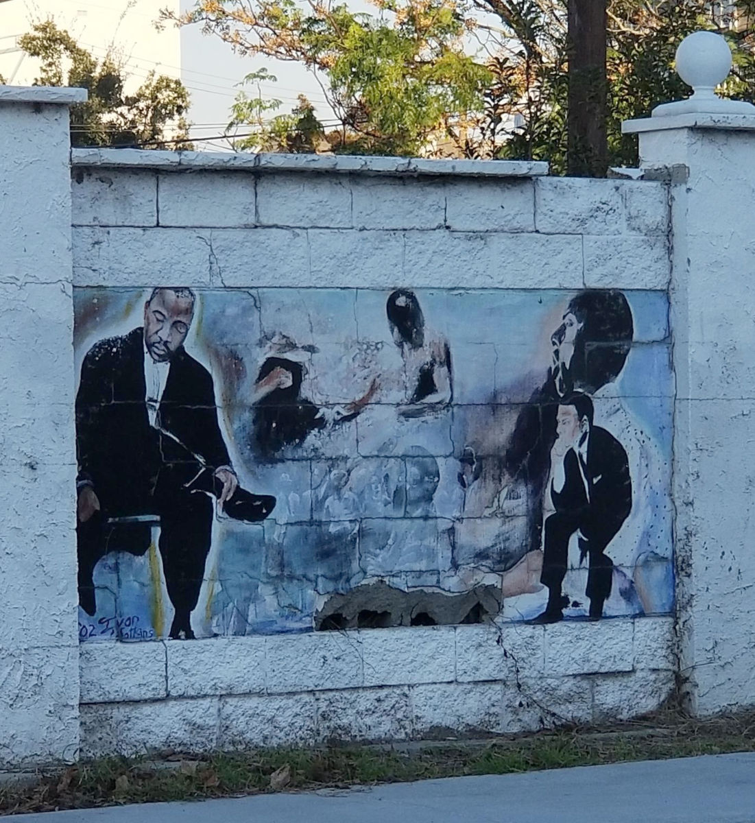 A mural on a white block wall, picturing MLK and other figures.