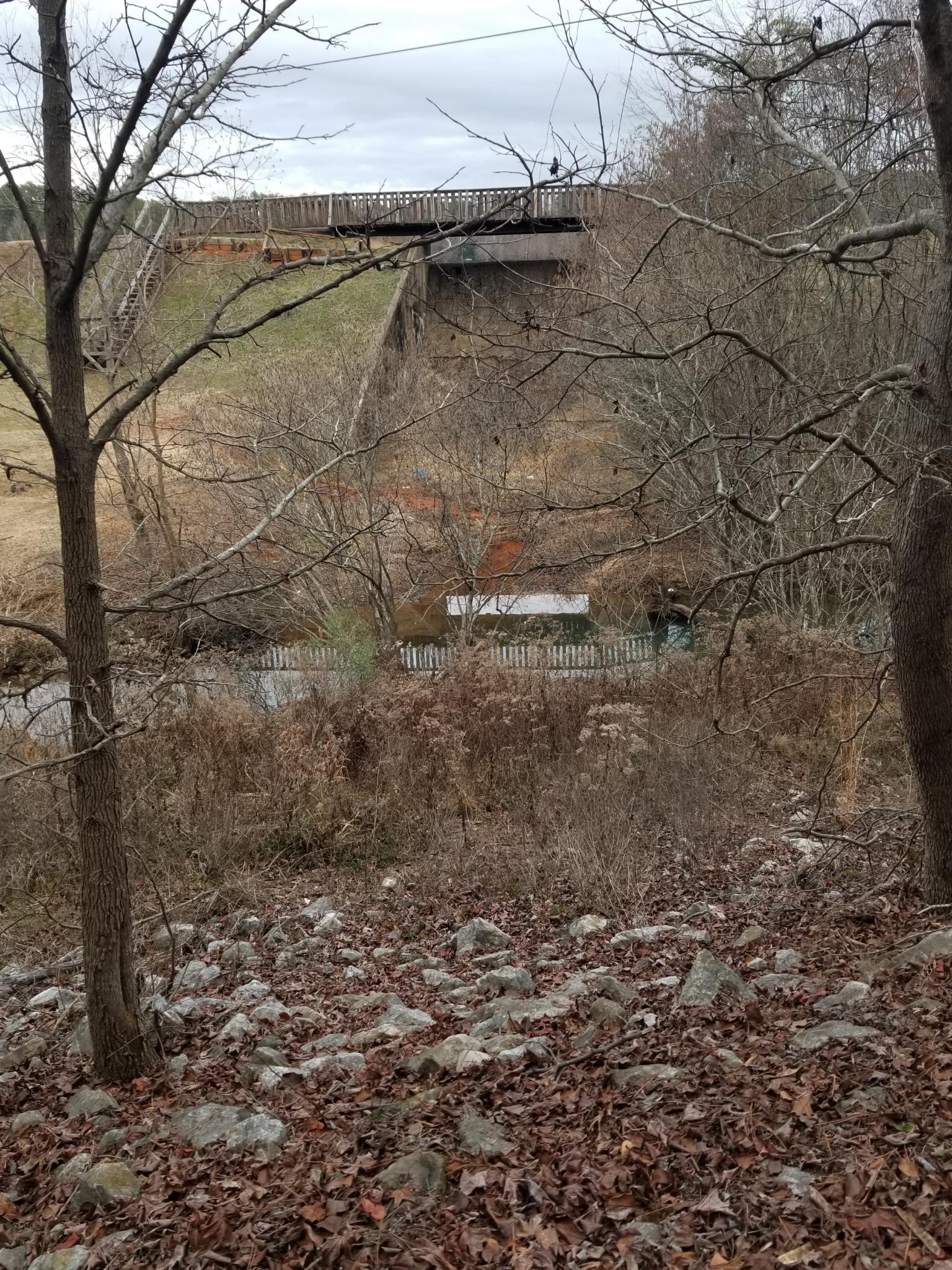 A lake spillway is seen, over which passes a foot-path.