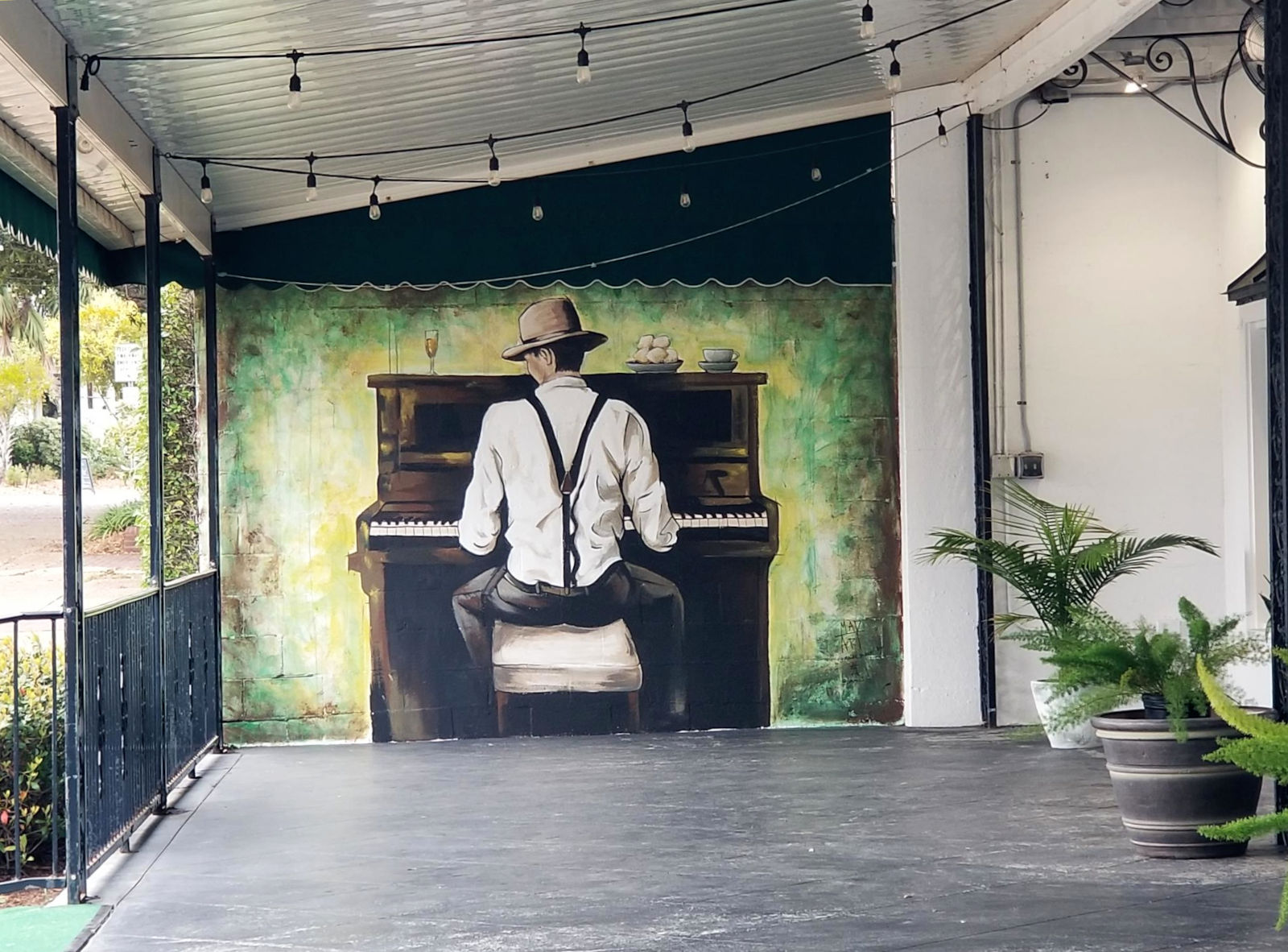 Mural on a patio creates the appearance of a man playing piano along the patio's edge..