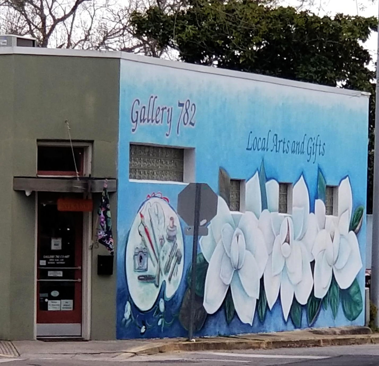 Mural portrays painting supplies and three larg magnolia blooms.