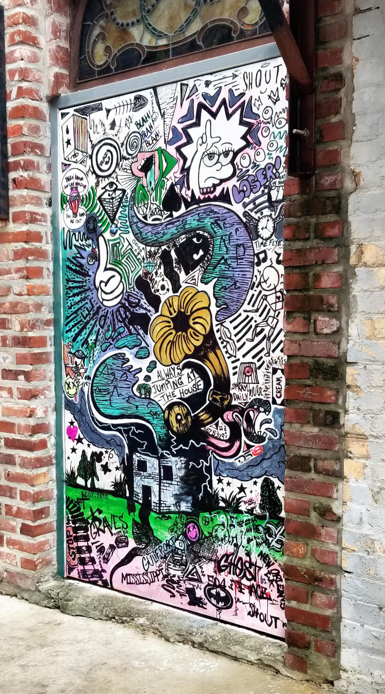 Mural painting showing a building at the bottom, from which spreads a frenetic arrangment of cartoon elements.