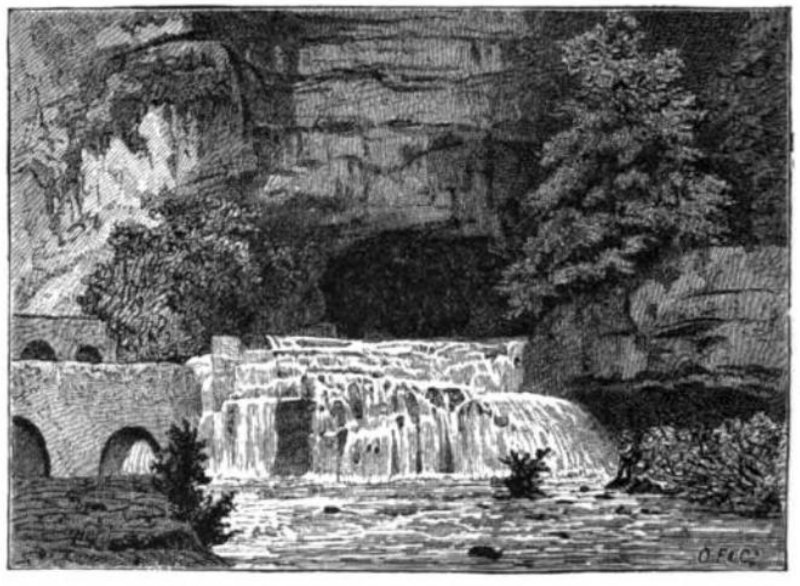 A river exits the from the face of a mountain.