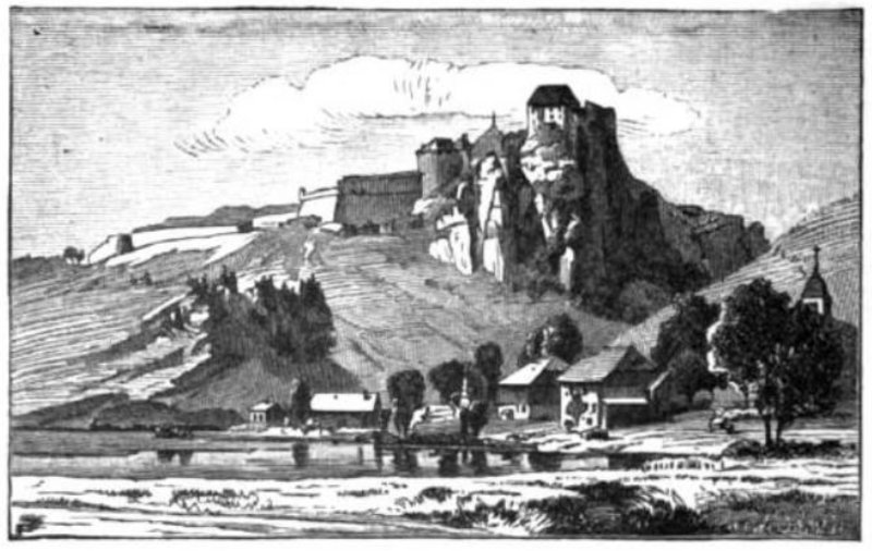A fortified structure is seen at a high elevation overlooking smaller buildings and trees below.