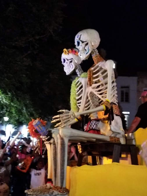 Du grandaj modelaj skeletoj vidiĝas sidantaj sur parada ĉaro dum ĝi vojaĝas laŭ strato en Nov-Orleano dum parado 'Krew of Boo'.