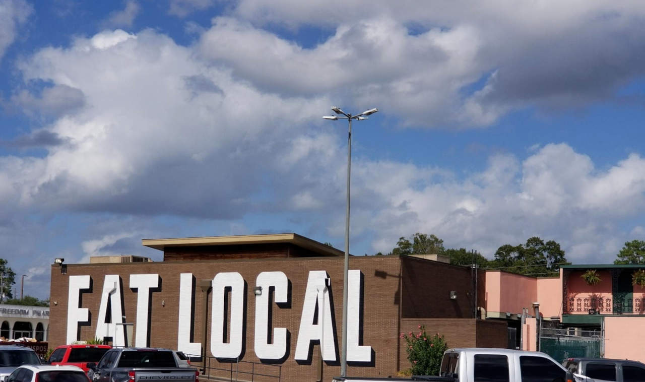 The brick wall of a restaurant covered with the words EAT LOCAL.