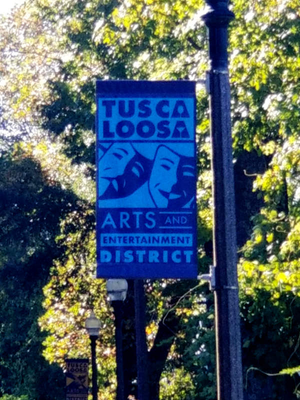 A sign shows the 'Tuscaloosa Arts and Entertainment District' featuring the comedy-drama theater masks.