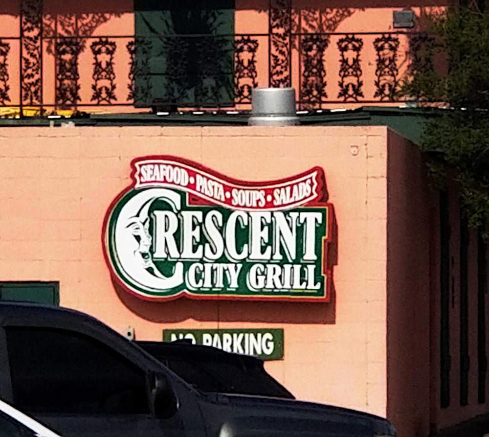 Restaurant sign, on a wall, under an iron railing.