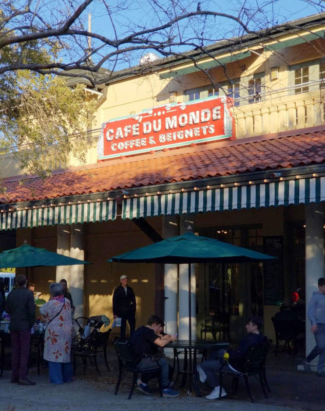 Café du Monde, verdaj ombreloj kaj homoj, en parko de Nov-Orleano.