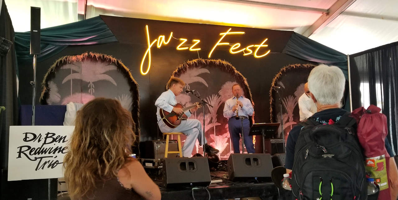 Triopo da vivaj muzikistoj ludas sur la scenejo.