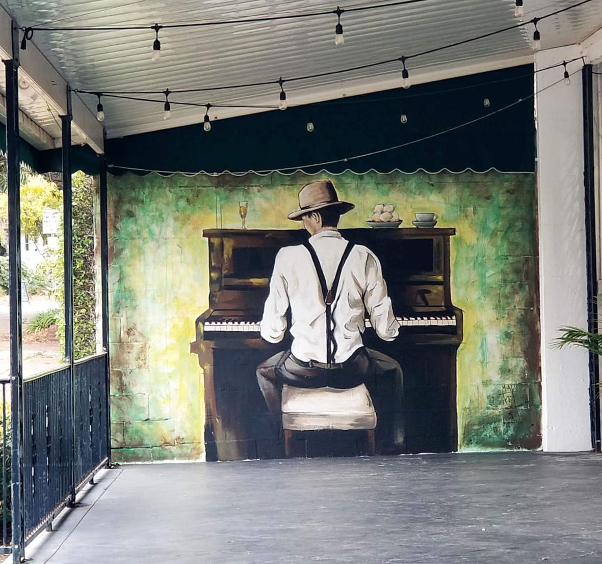 Murpentraĵo aspektas kvazaŭ viro ludas pianon laŭ la rando de porĉo.