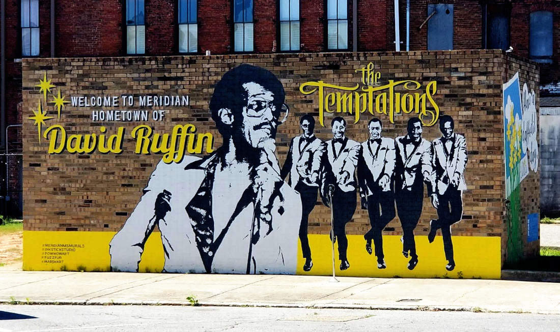 A mural says 'Welcome to Meridian, Hometown of David Ruffin - The Temptations' showing these musicians.