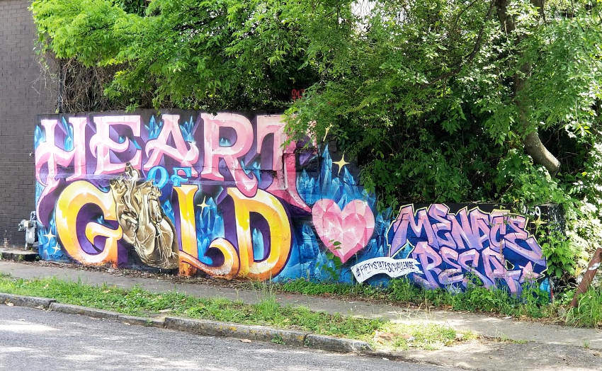 A mural shows the words 'Heart of Gold', the word 'gold' is gold colored and the 'O' is replaced by a human heart.