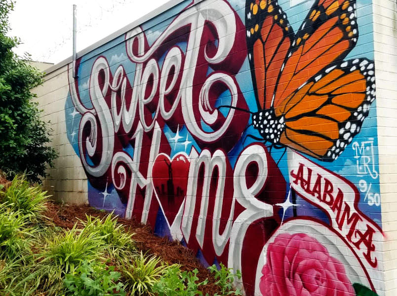 Mural shows "Sweet Home Alabama" with a large butterfly and flower.