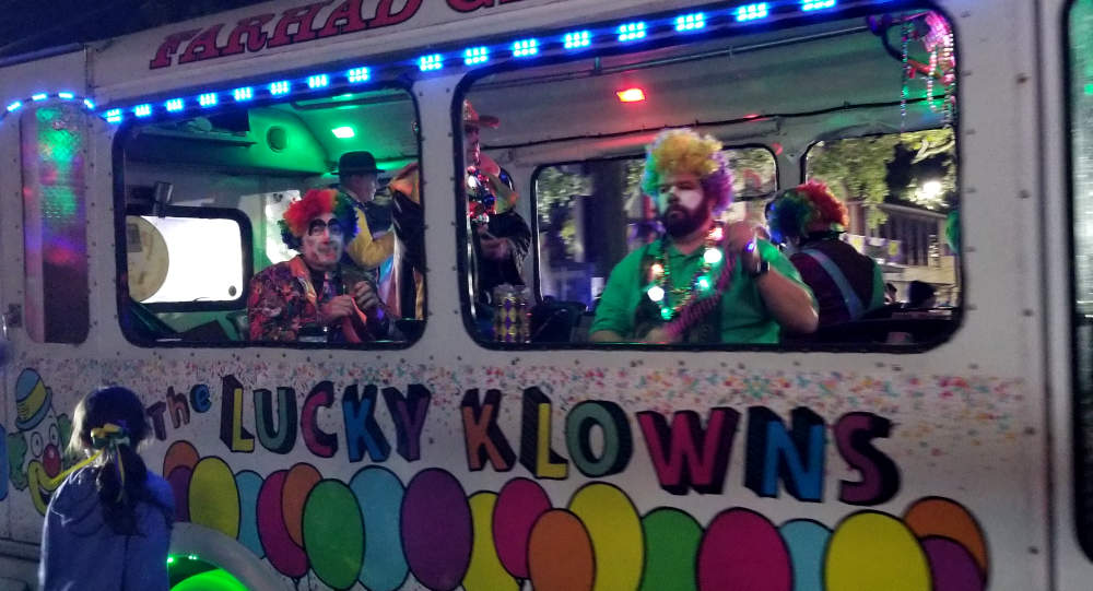 Klaŭnoj en blanka buso kun balonoj.