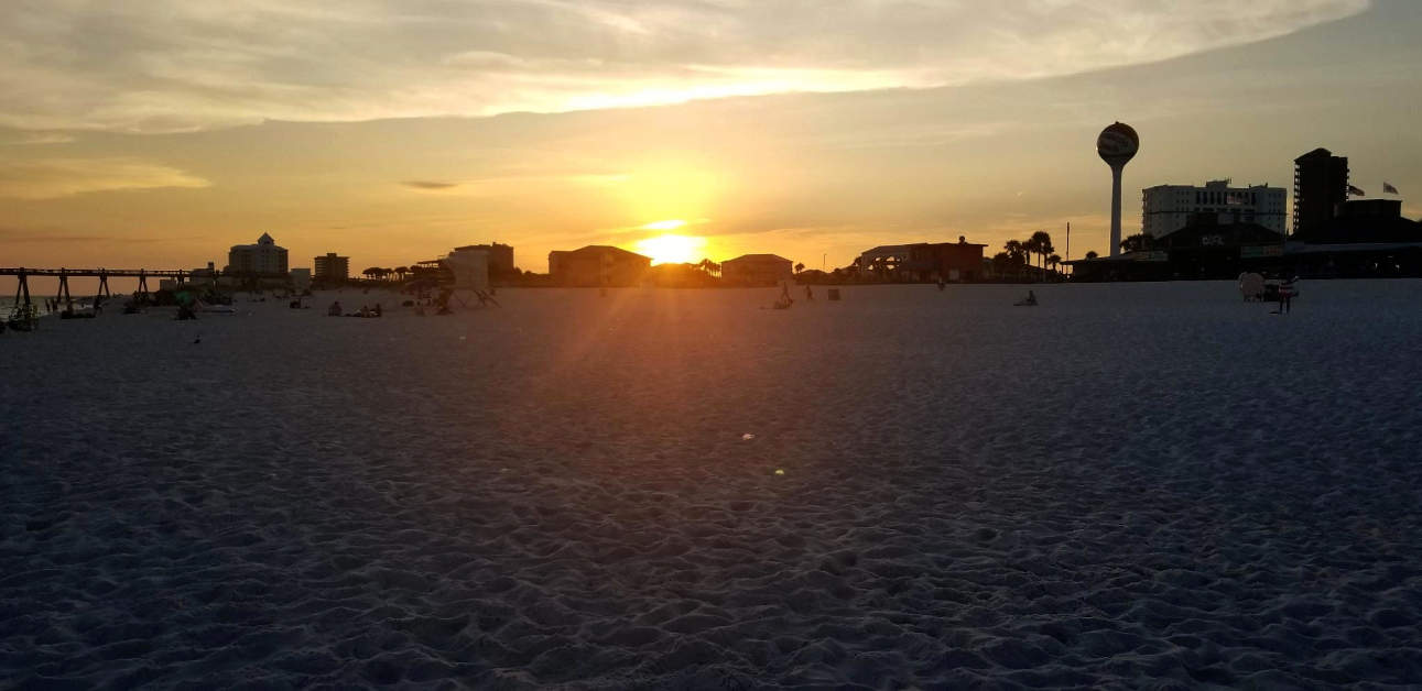 The sun sets behind building at Pensacola Beach, Florida.