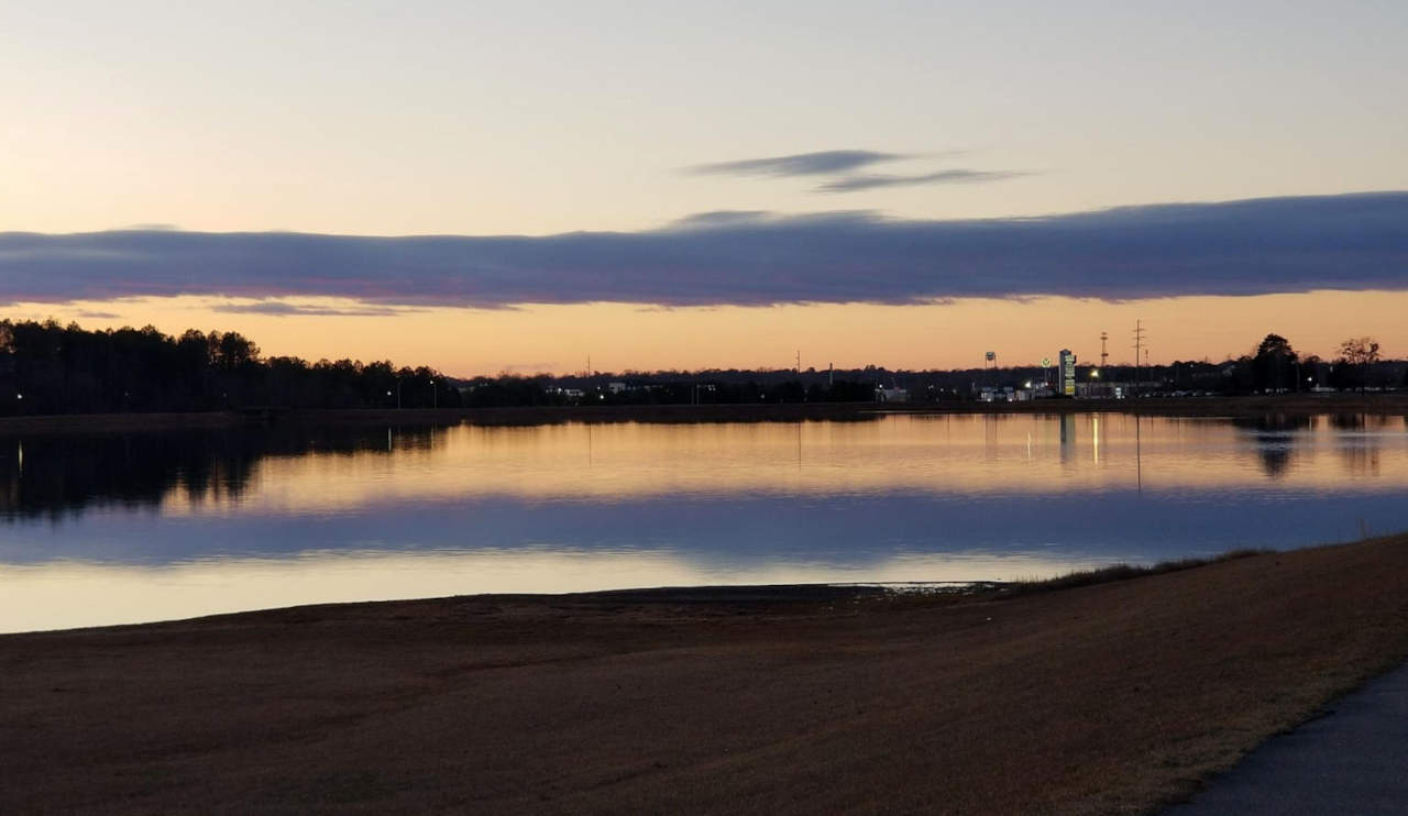 A blue and orange sky at sunset reflected on the surface of a lake.