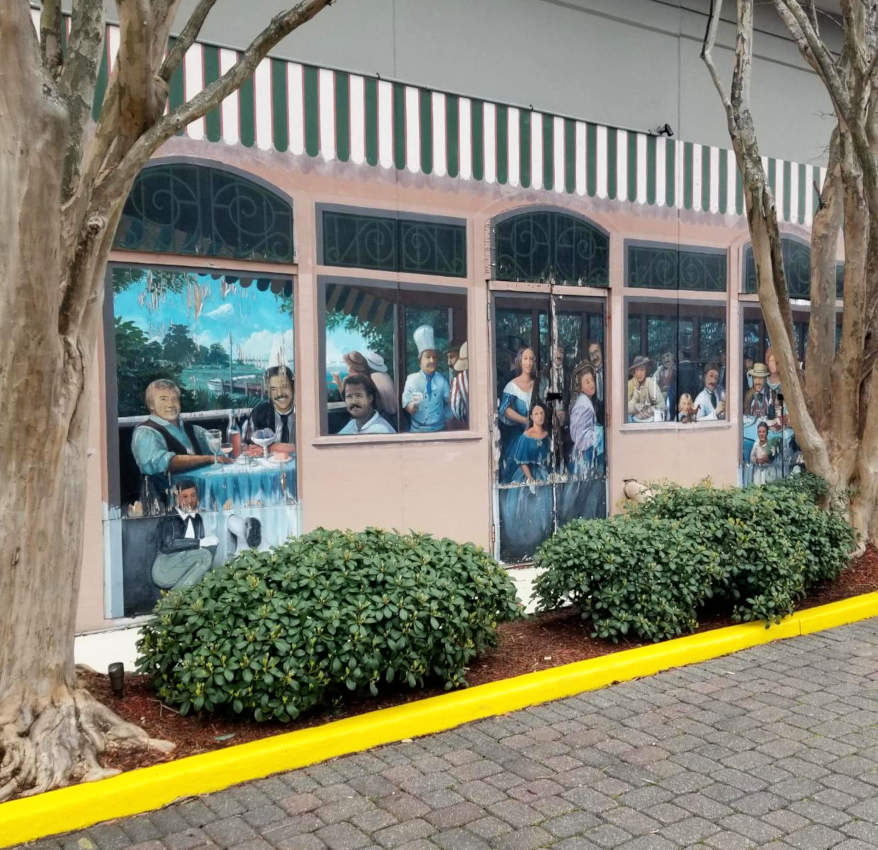 A painting along the wall of a driveway, so that diners seem to be visible through the windows.